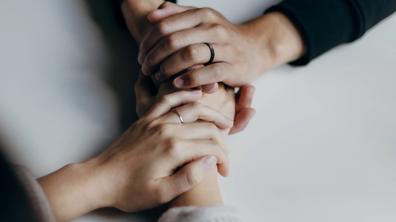 Due persone si tengono per mano su un tavolo in un gesto di sostegno.